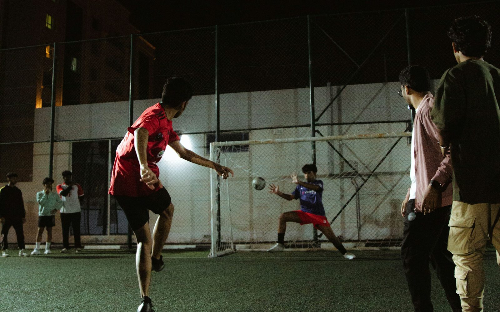 Young people playing football in the evening under floodlights