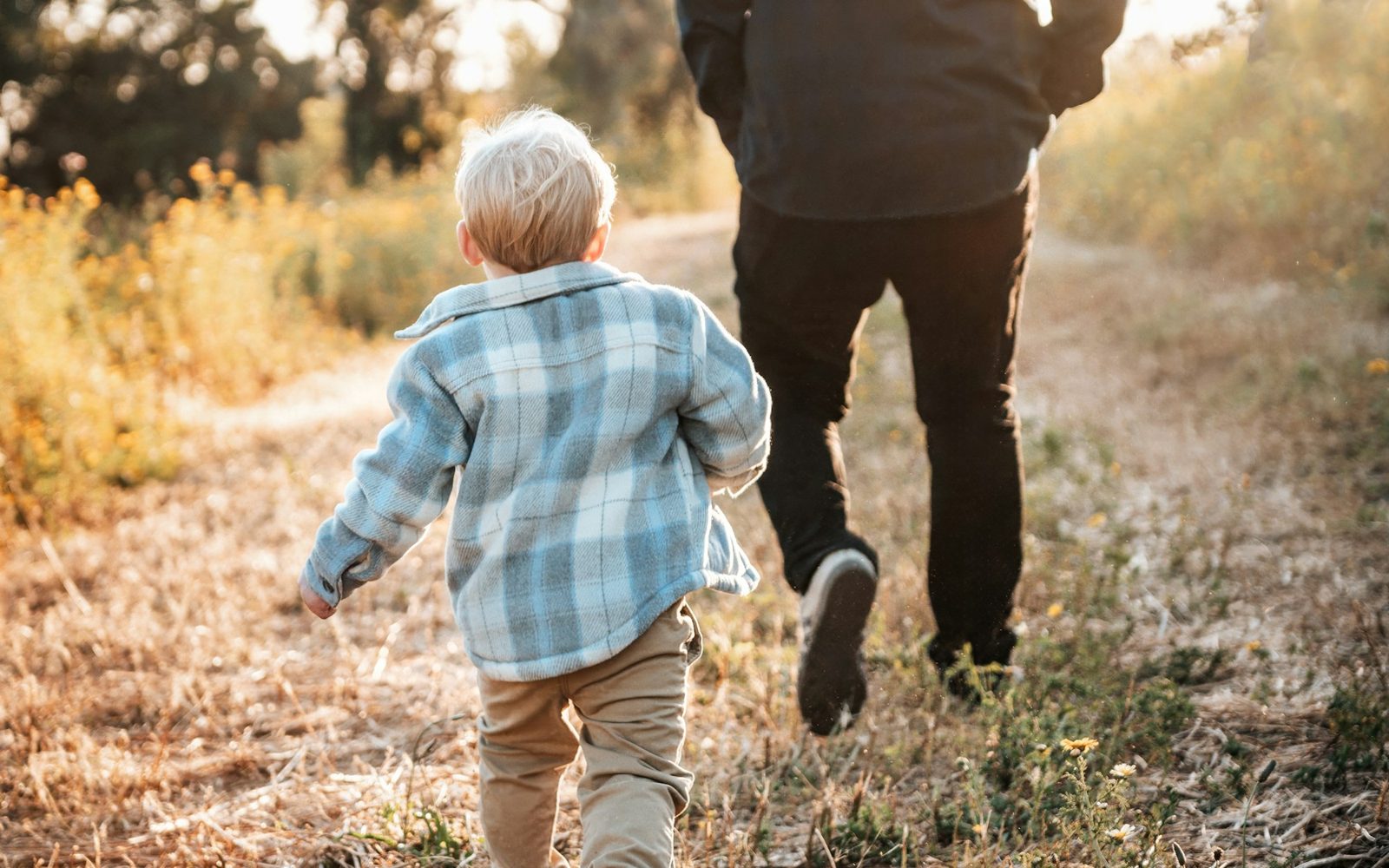 A father and young child walking together along a country path